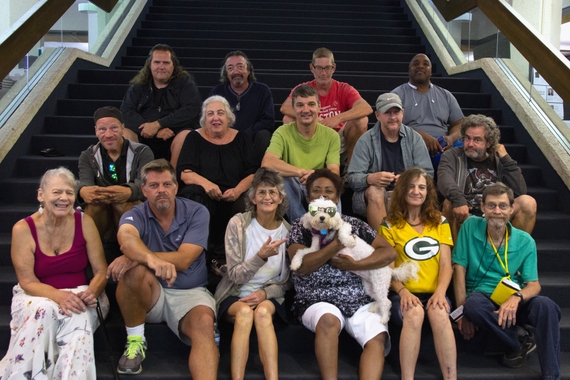 A group of people sit on a set of stairs, smiling at the camera.